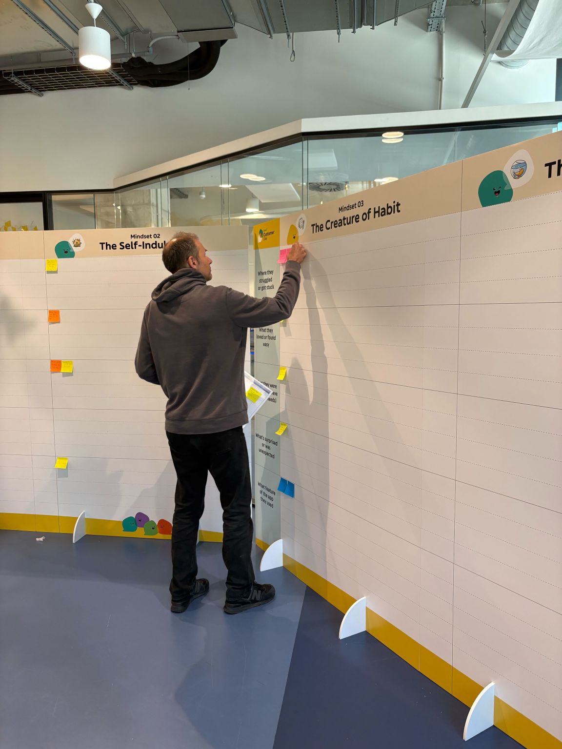 Team member adding notes to a mindset wall at Customer Day